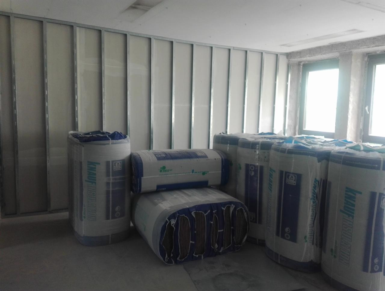 Wnętrze w trakcie remontu z widoczną konstrukcją ścian działowych i stosem izolacji wełnianej Knauf Insulation w folii.