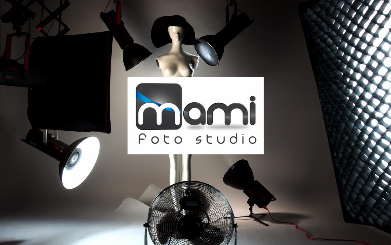 Studio fotograficzne: manekin z kapeluszem otoczony lampami studyjnymi, wentylatorem i softboxem, z widocznym logo 'Mami Foto Studio'.