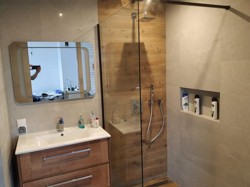 Wykończona łazienka w Świebodzicach z kabiną prysznicową typu walk-in z drewnopodobnymi panelami, umywalką z szafką w stylu rustykalnym i wnęką z kosmetykami.