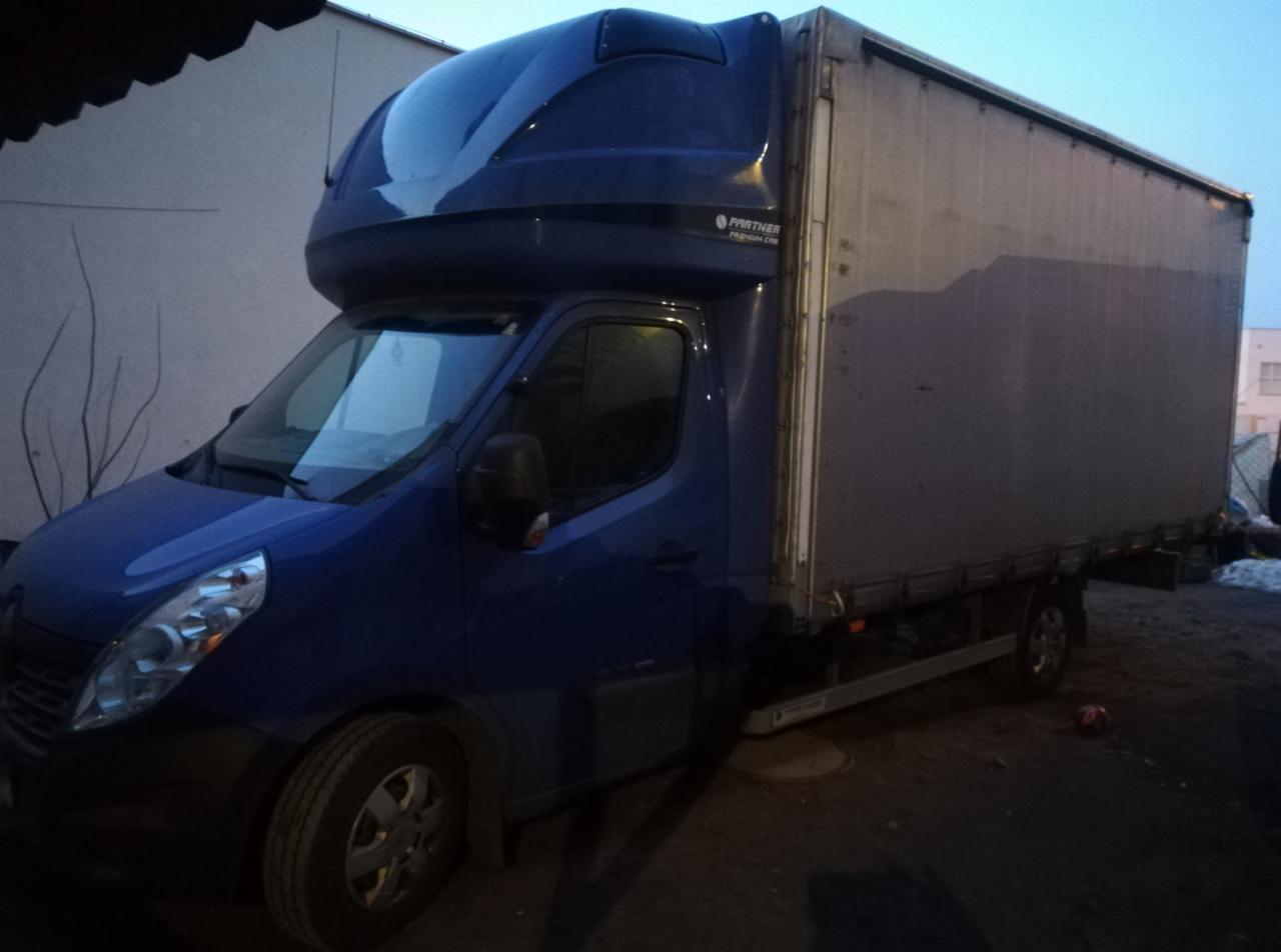 Niebieski bus dostawczy Renault Master z zabudową kontenerową i aerodynamicznym dachem, zaparkowany na zewnątrz w pochmurny dzień.