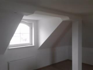 Białe, gładkie ściany i sufit na poddaszu z oknem łukowym, widoczne elementy konstrukcyjne po gładziowaniu i malowaniu.