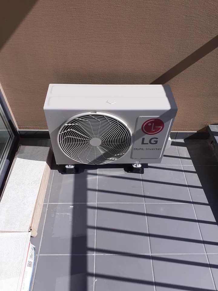 Kompaktowa jednostka zewnętrzna klimatyzacji LG Dual Inverter zainstalowana na balkonie w Sulejówku, widoczne cienie rzucane przez barierki.