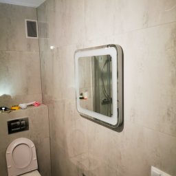 TIMWEK KATARZYNA KORBUT - Wykończona łazienka w Pęgowie z płytkami imitującymi marmur, wisząca toaleta i podświetlane lustro z odbiciem prysznica.