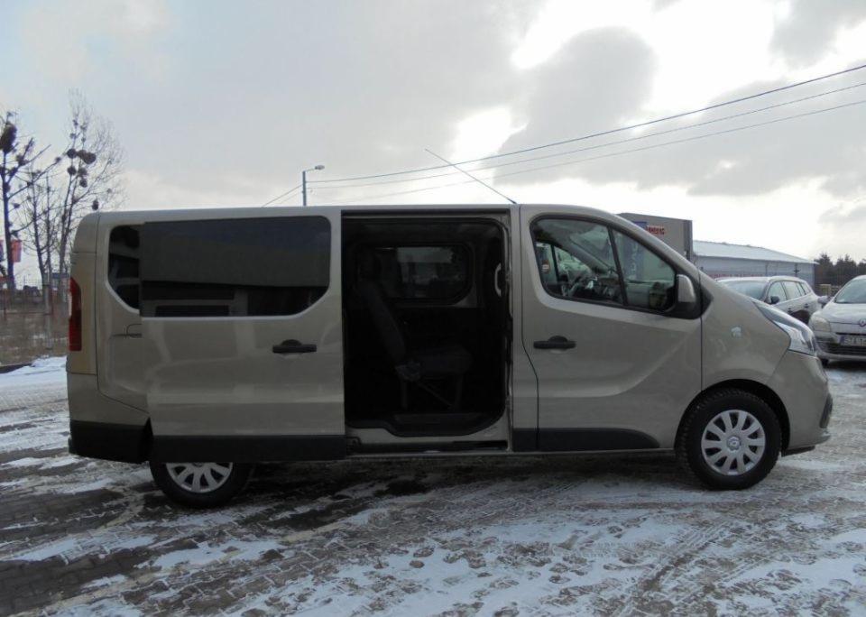 Beżowy van z otwartymi drzwiami przesuwnymi, zaparkowany na śniegu w pochmurny dzień.