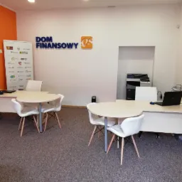 Jasne biuro Domu Finansowego w Lublinie z dwoma okrągłymi stołami i krzesłami, widoczne logo firmy na ścianie i plakaty informacyjne.