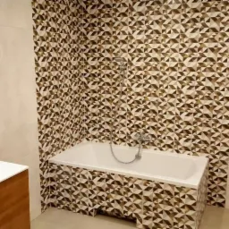 Nowoczesna łazienka z geometrycznymi brązowo-białymi płytkami na ścianie i obudowie wanny, kremowe płytki na pozostałych ścianach, biała wanna i umywalka z szafką z jasnego drewna, lustro...