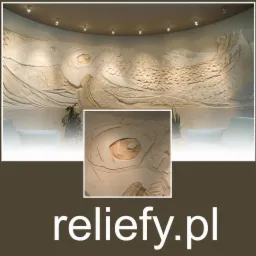 Duży, jasny relief ścienny przedstawiający stylizowany statek na falach, oświetlony punktowymi lampami sufitowymi w tle widać fragment białej sofy i roślinę doniczkową.