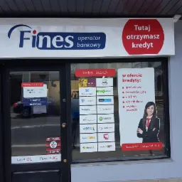 Fasada placówki finansowej Fines z witryną informującą o kredytach gotówkowych, konsolidacyjnych, dla firm i rolników, prezentująca logotypy różnych banków i firm pożyczkowych.