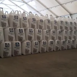 Rzędy ułożonych worków z nawozem YaraMila Viking NPK 14-14-21 w magazynie z białym dachem namiotowym.