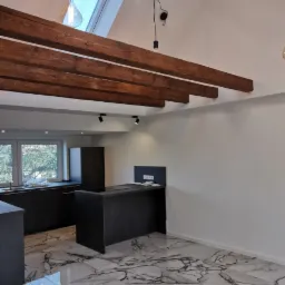 Nowoczesne oświetlenie wiszące z żarówkami Edisona w nowej kuchni z marmurową podłogą i drewnianymi belkami stropowymi.