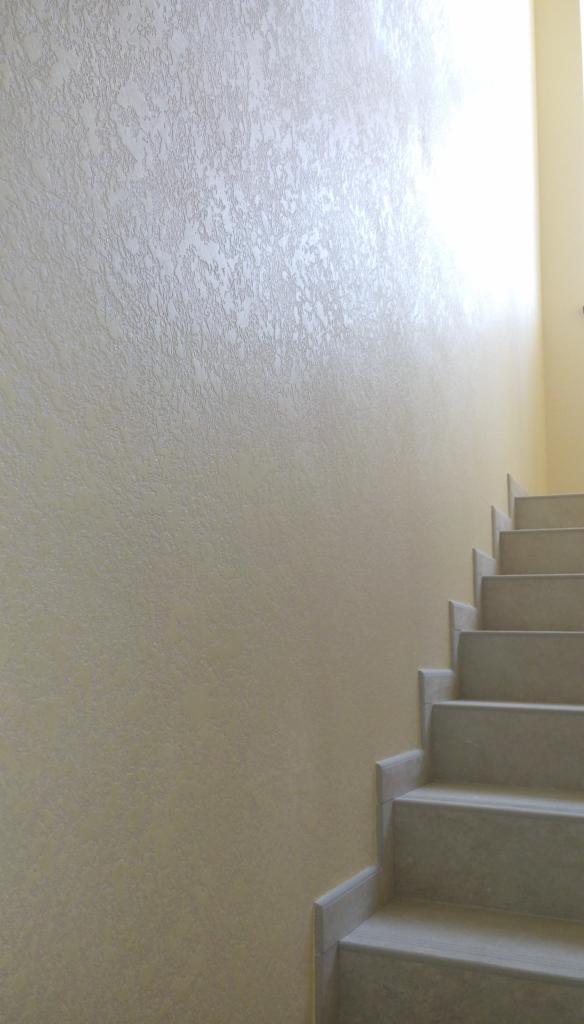 Teksturowana ściana w odcieniach beżu z widocznymi schodami z jasnego kamienia