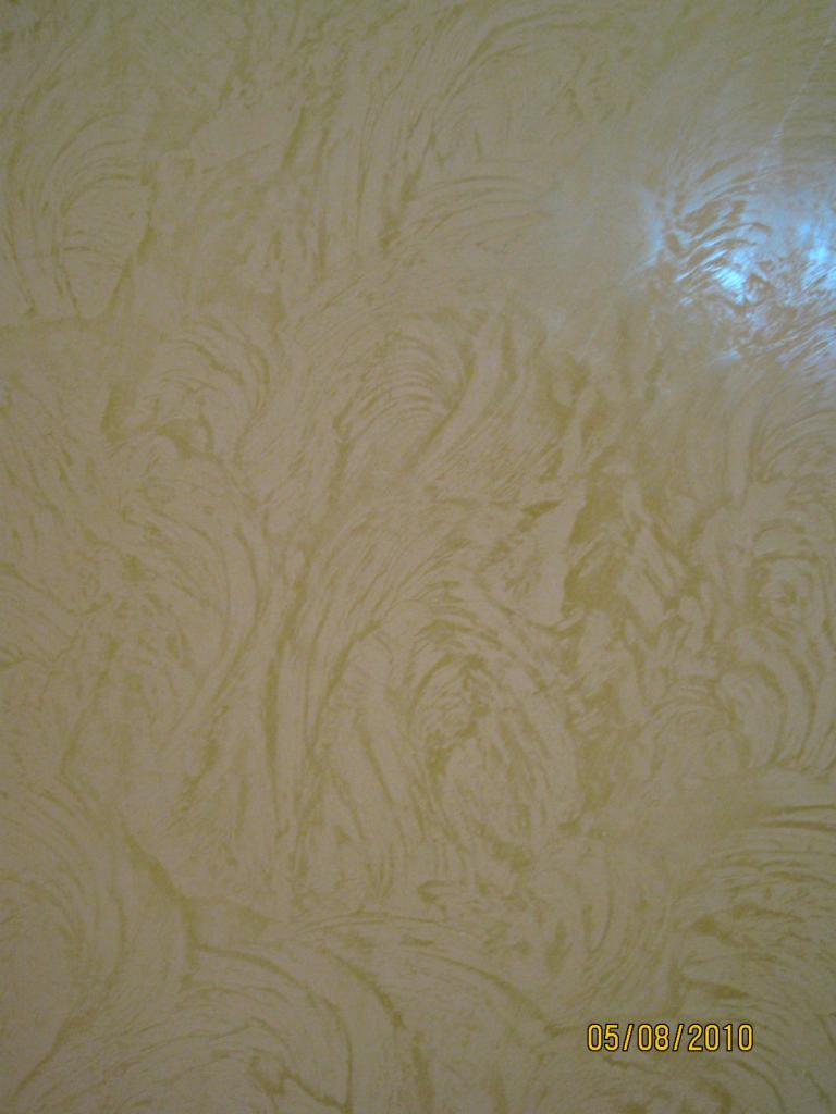 Delikatna, kremowa ściana z dekoracyjną fakturą przypominającą pociągnięcia pędzla, oświetlona z góry, z widoczną datą 05/08/2010 w prawym dolnym rogu.