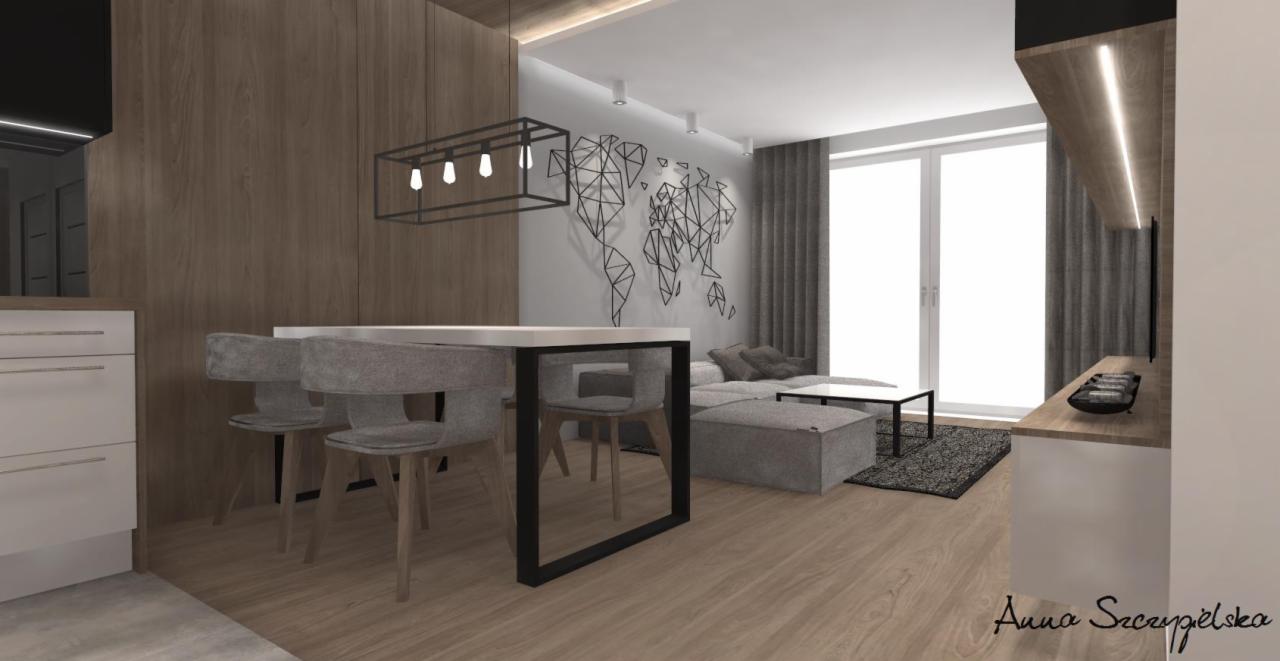Wizualizacja wnętrza: stół z szarymi krzesłami, drewniana zabudowa kuchenna, sofa z pufem, lampa wisząca w kształcie prostokąta i dekoracja ścienna w formie mapy świata.