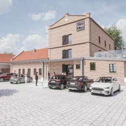 Rynkowski Design - Wizualizacja budynku usługowego Stary Młyn z parkingiem i patio z parasolami, wykonana w ciepłych barwach cegły z nowoczesnymi elementami architektonicznymi.