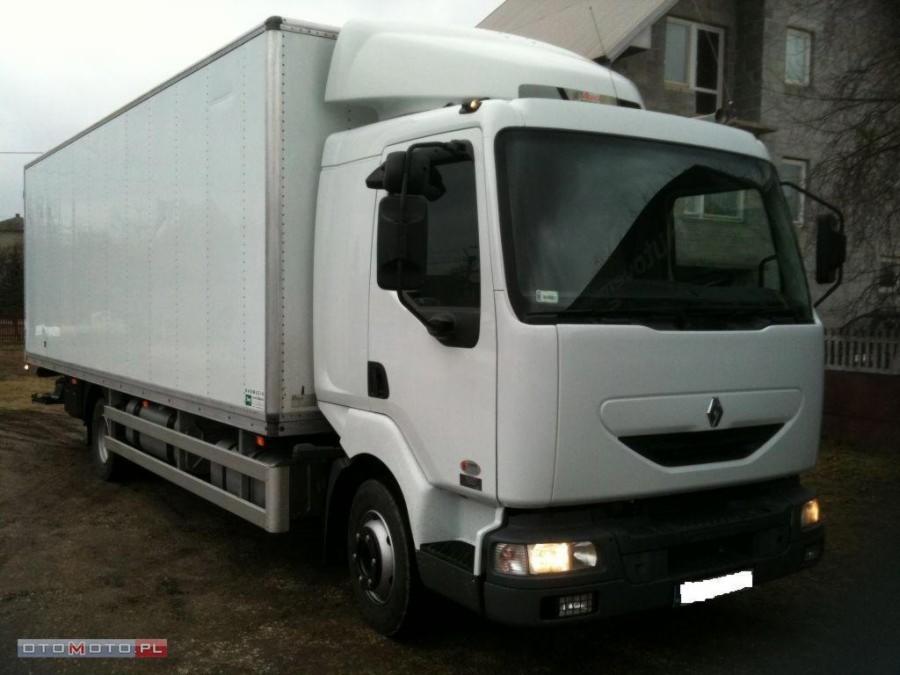 Biała ciężarówka Renault z zabudową kontenerową, zaparkowana na ziemistym podłożu przed domem, widok z przodu.