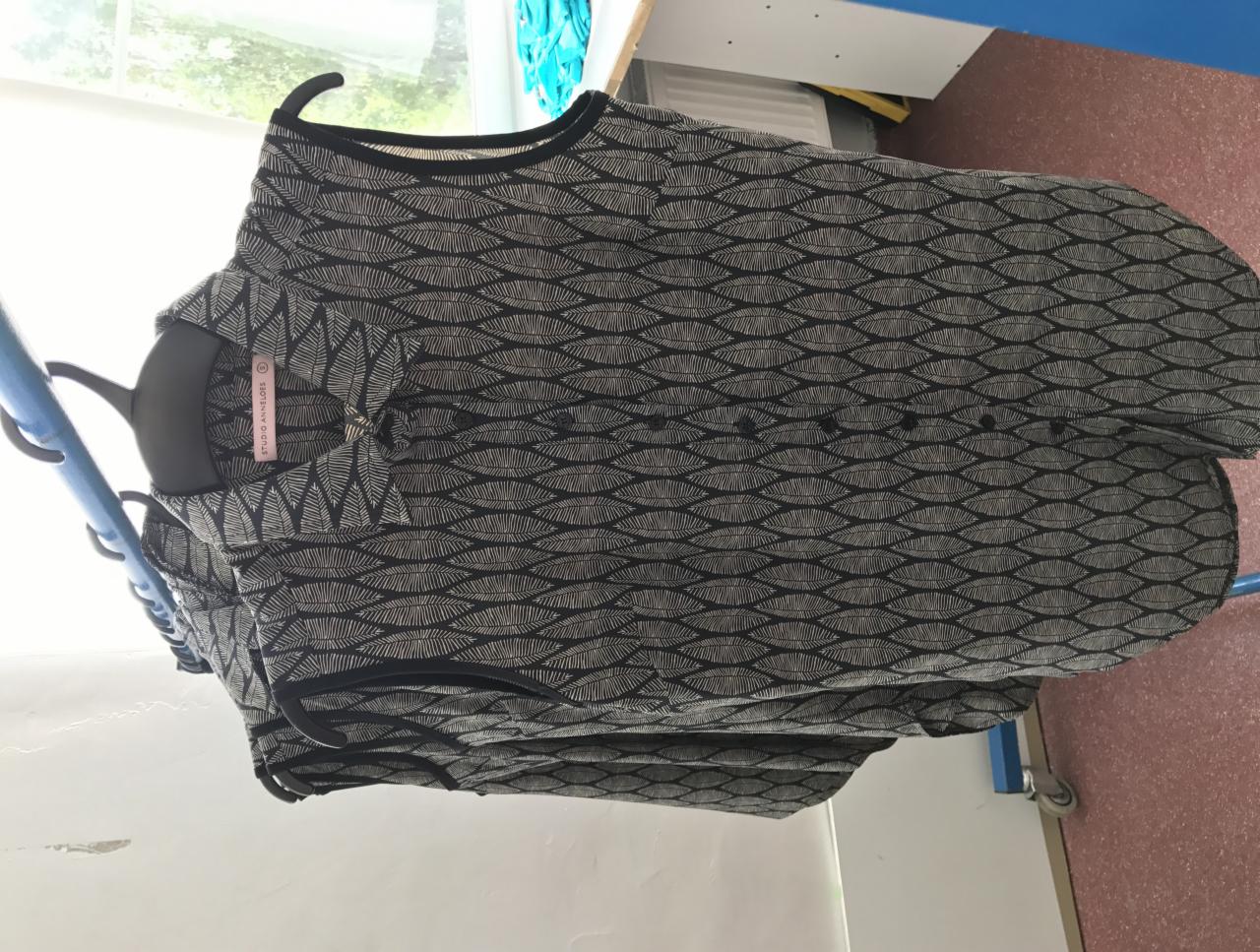 Uszyta koszula z czarno-białym wzorem liści na wieszaku, widoczna metka 'Studio Anneloes'.