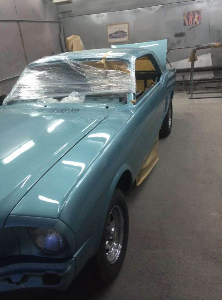 Jasnoniebieski klasyczny samochód z otwartą maską, owinięty folią ochronną na przedniej szybie, w warsztacie przed dalszymi pracami.