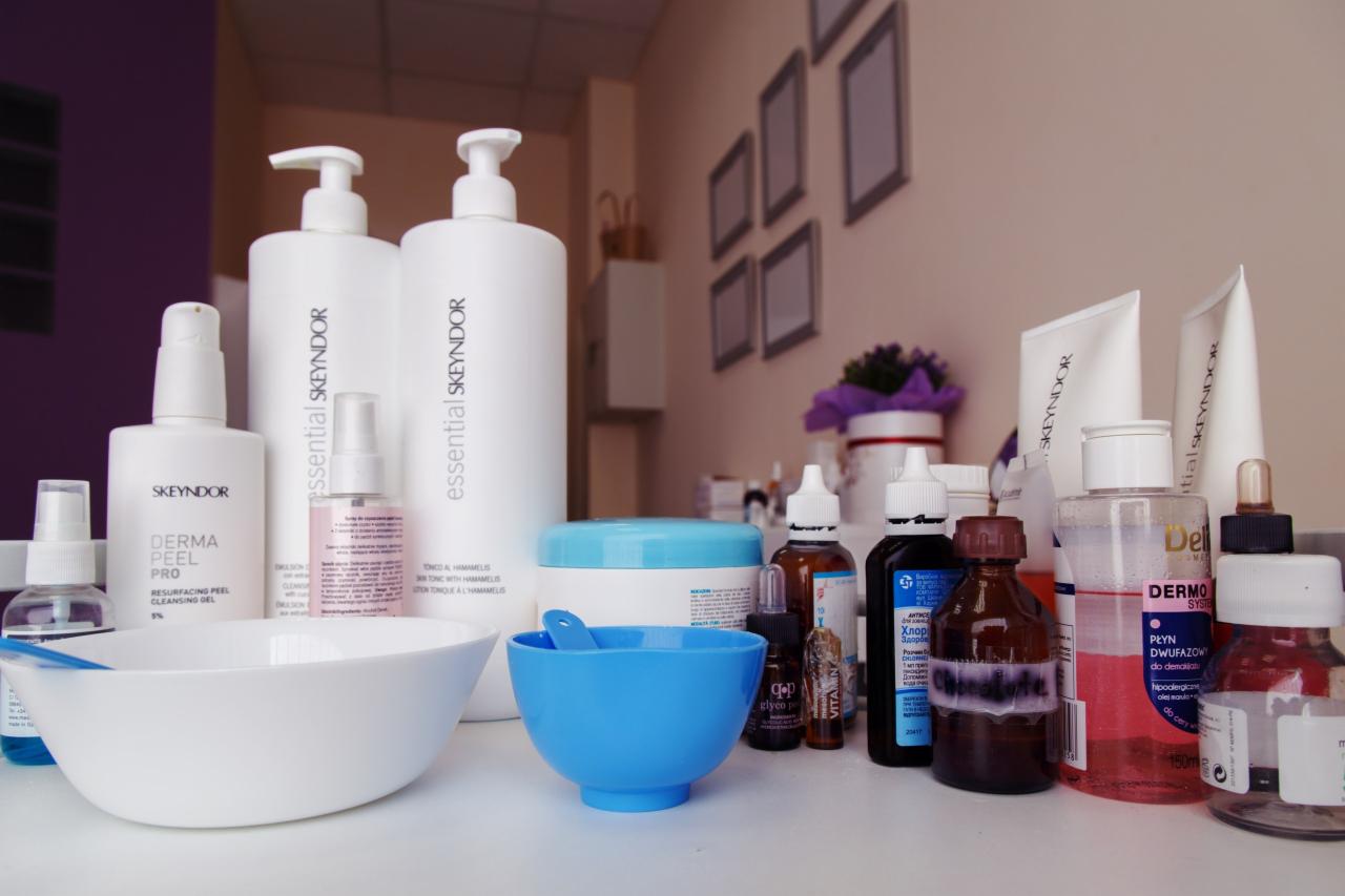 Zestaw kosmetyków i preparatów Skeyndor na białym stole, widoczne białe i niebieskie miseczki oraz szpatułki, w tle ściana z dekoracjami i kwiatami.