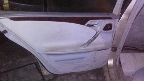 Wnętrze brudnych drzwi samochodu z jasną tapicerką i drewnianym wykończeniem.