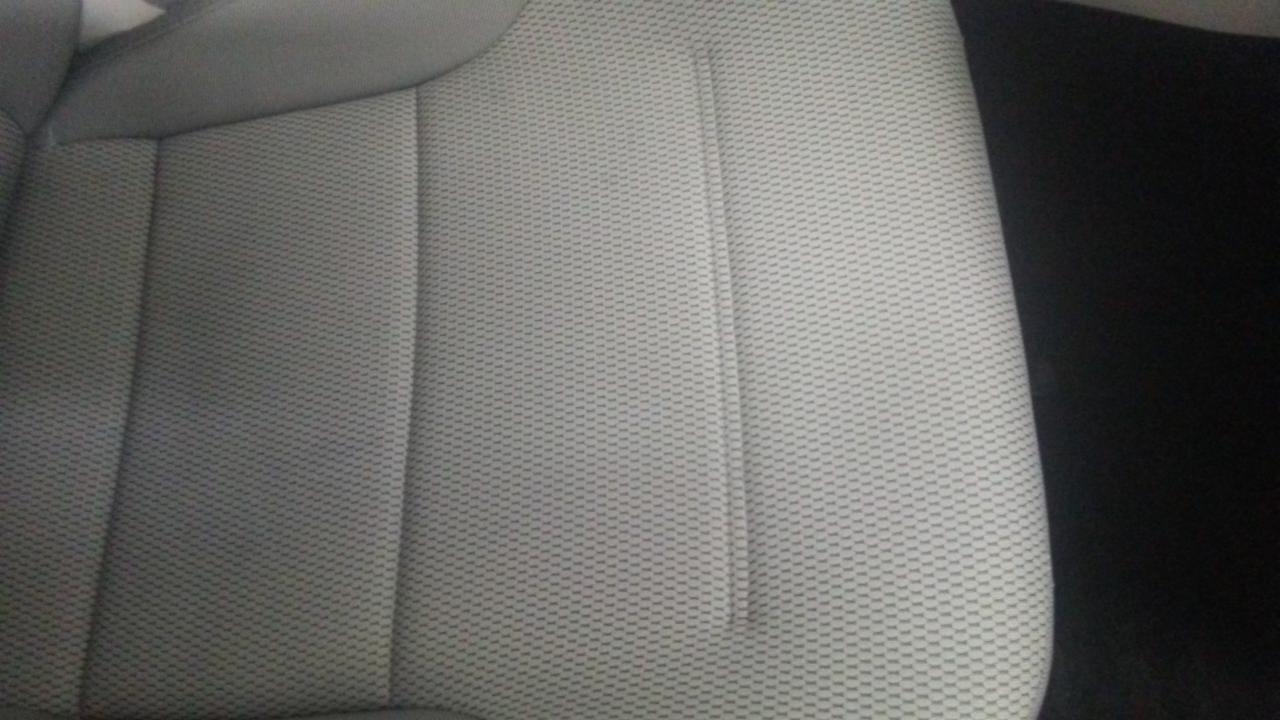 Fragment jasnoszarego fotela samochodowego z wyraźną strukturą tkaniny i ciemnym tłem