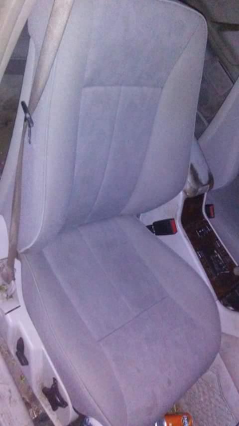 Szare, welurowe siedzenie samochodowe z widocznym pasem bezpieczeństwa i elementami deski rozdzielczej z imitacją drewna.