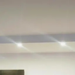 Biały sufit podwieszany z wbudowanymi punktowymi lampami LED w nowo wykończonym wnętrzu, widoczne kratki wentylacyjne na ścianie.