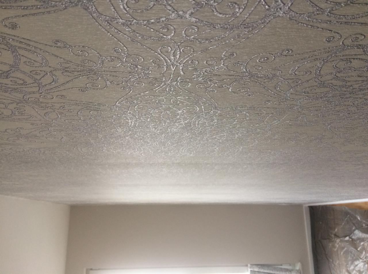 Srebrzysty wzór na suficie w pomieszczeniu w Krakowie, przypominający tapetę z motywem ornamentów, widoczny z perspektywy osoby leżącej na podłodze.