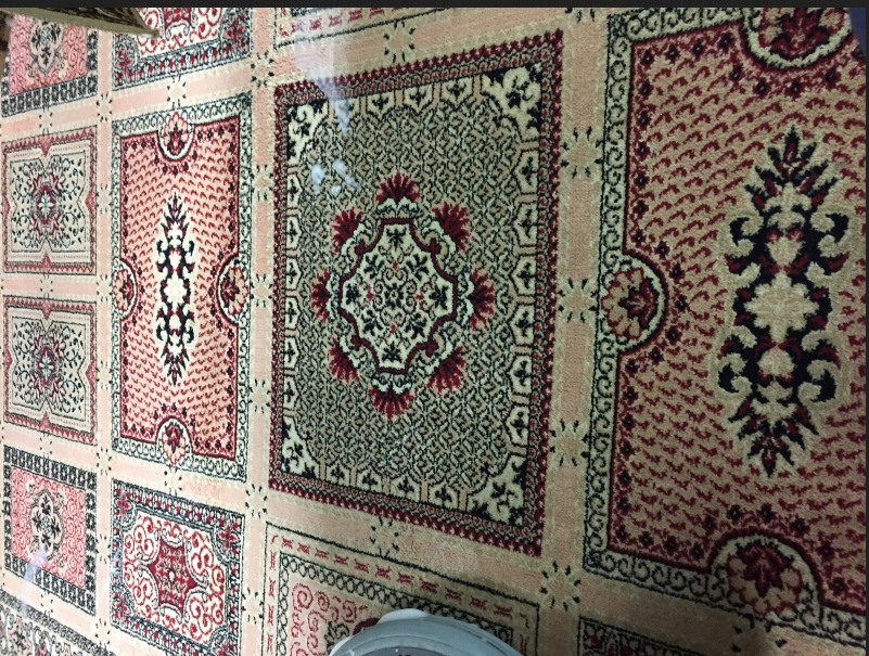 Wzór dywanu w odcieniach beżu i czerwieni, z motywami orientalnymi, widziany z góry w Krosno.