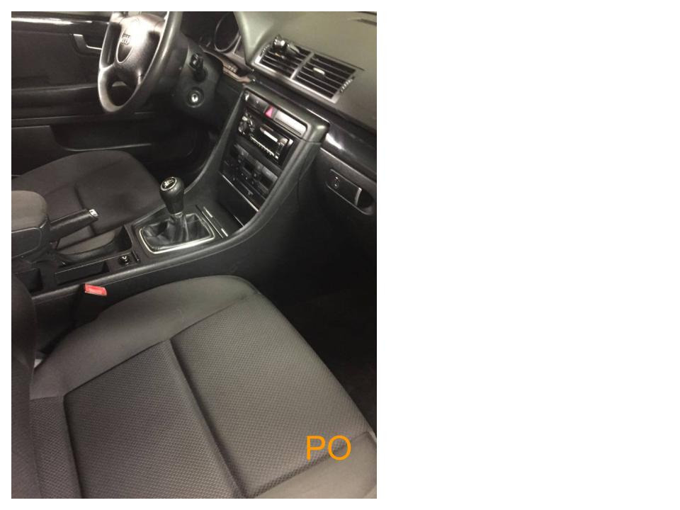 Wnętrze samochodu z czarną tapicerką, widoczne fotele, kierownica i deska rozdzielcza, wnętrze wymaga odświeżenia.