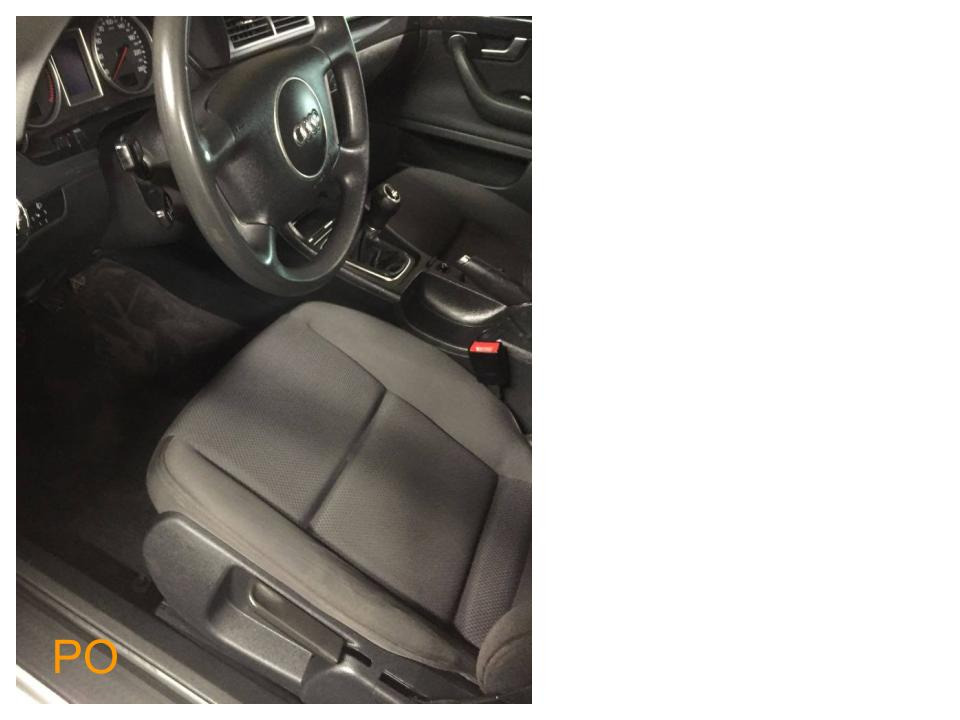 Wnętrze samochodu Audi A4 z szarą tapicerką tekstylną na przednim siedzeniu, widoczna kierownica z logo marki i dźwignia zmiany biegów.