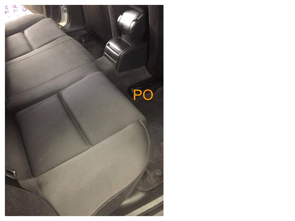 Wnętrze samochodu: Tylna, szara tapicerka siedzeń z podłokietnikiem, widoczne ślady użytkowania na dywaniku.
