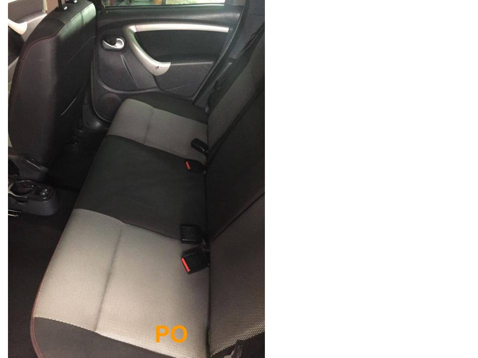 Wnętrze samochodu z widocznymi tylnymi siedzeniami z szaro-czarną tapicerką. Widoczne pasy bezpieczeństwa i uchwyt drzwi. Tapicerka dwukolorowa, z ciemną górą i jasnym dołem.