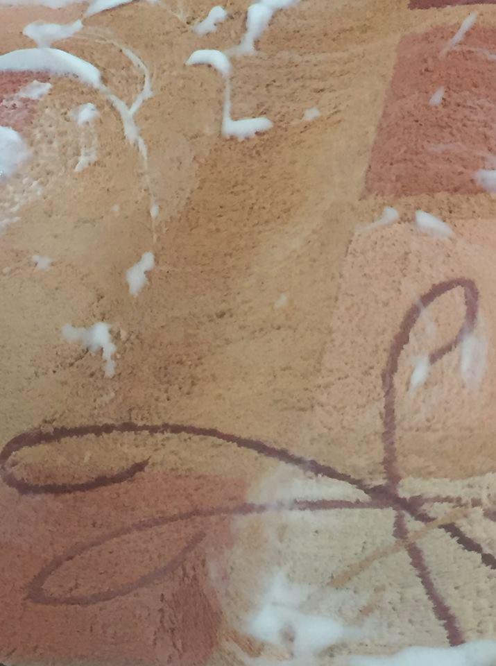 Fragment wzorzystego dywanu z widocznymi plamami piany czyszczącej podczas procesu odświeżania.