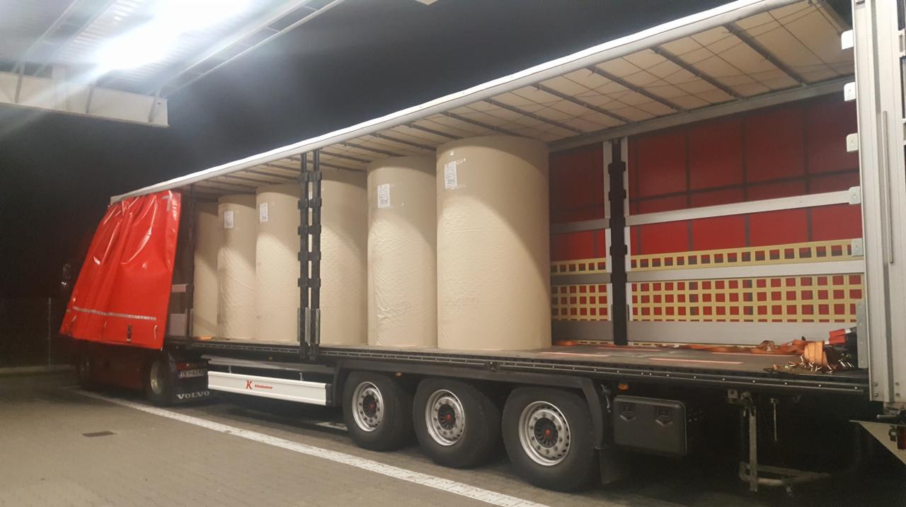 Ciężarówka Volvo z naczepą typu firanka załadowana rolami papieru, widoczne zabezpieczenia ładunku