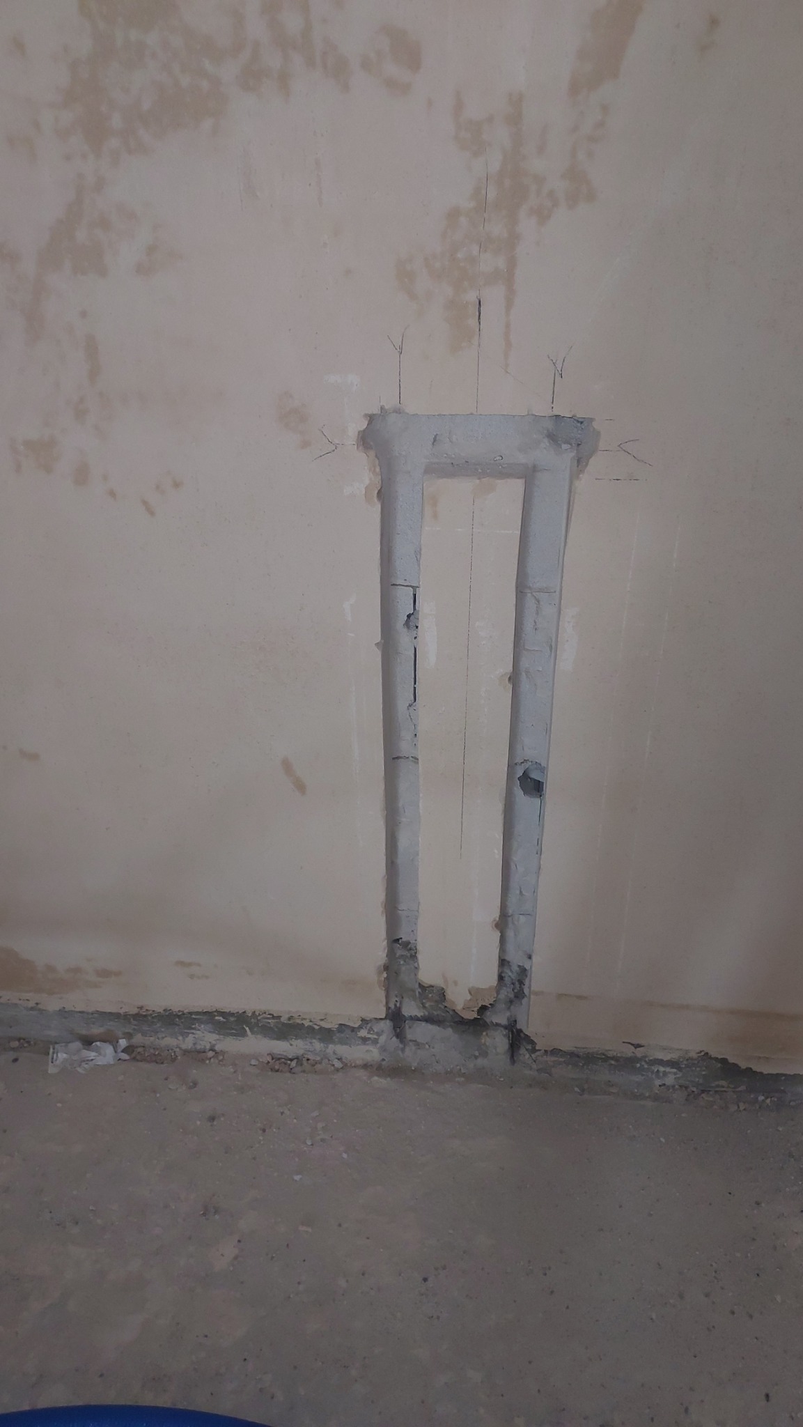 Wykonana bruzda w ścianie i podłodze pod rury instalacji, widoczne wystające druty zbrojeniowe.