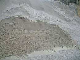 Jasnoszary piasek budowlany usypany w pryzmę, widoczny z bliska, z delikatną fakturą i nierówną powierzchnią. Tło lekko rozmyte, podkreśla strukturę materiału.