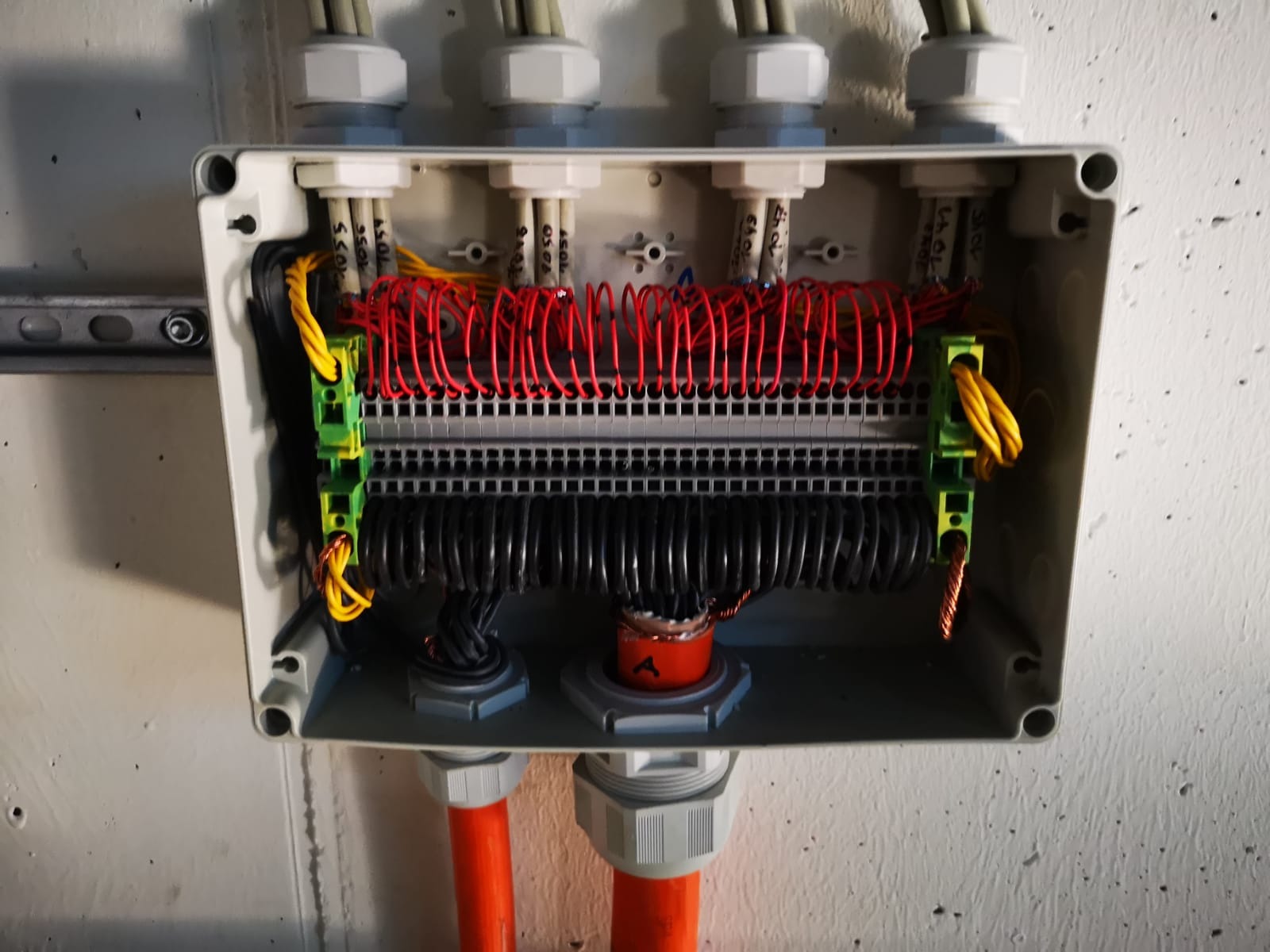 Detal skrzynki elektrycznej z precyzyjnie ułożonymi przewodami czerwonymi i czarnymi, widoczne złącza kablowe i oznaczenia na przewodach.