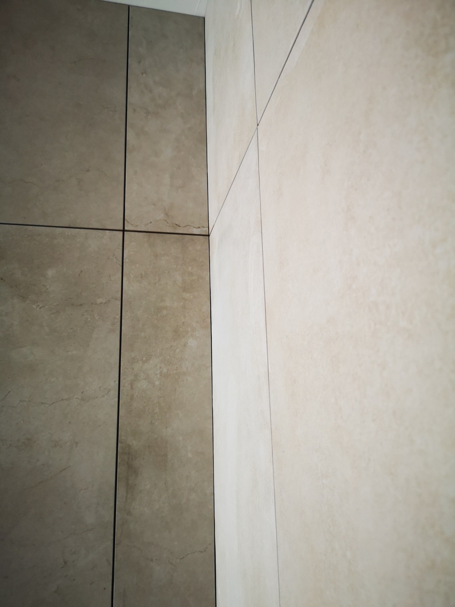 Beżowe, matowe płytki ceramiczne na ścianie w Mostach. Widoczne fugi i delikatna struktura kamienia. Ujęcie z bliska, podkreślające detale wykończenia.