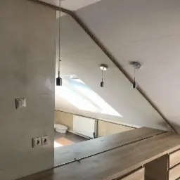 Lustro na wymiar w łazience na poddaszu, z widocznym skosem sufitu i dekoracyjnym sznurem wzdłuż krawędzi. Widoczne oświetlenie punktowe i fragment umywalki w odbiciu.