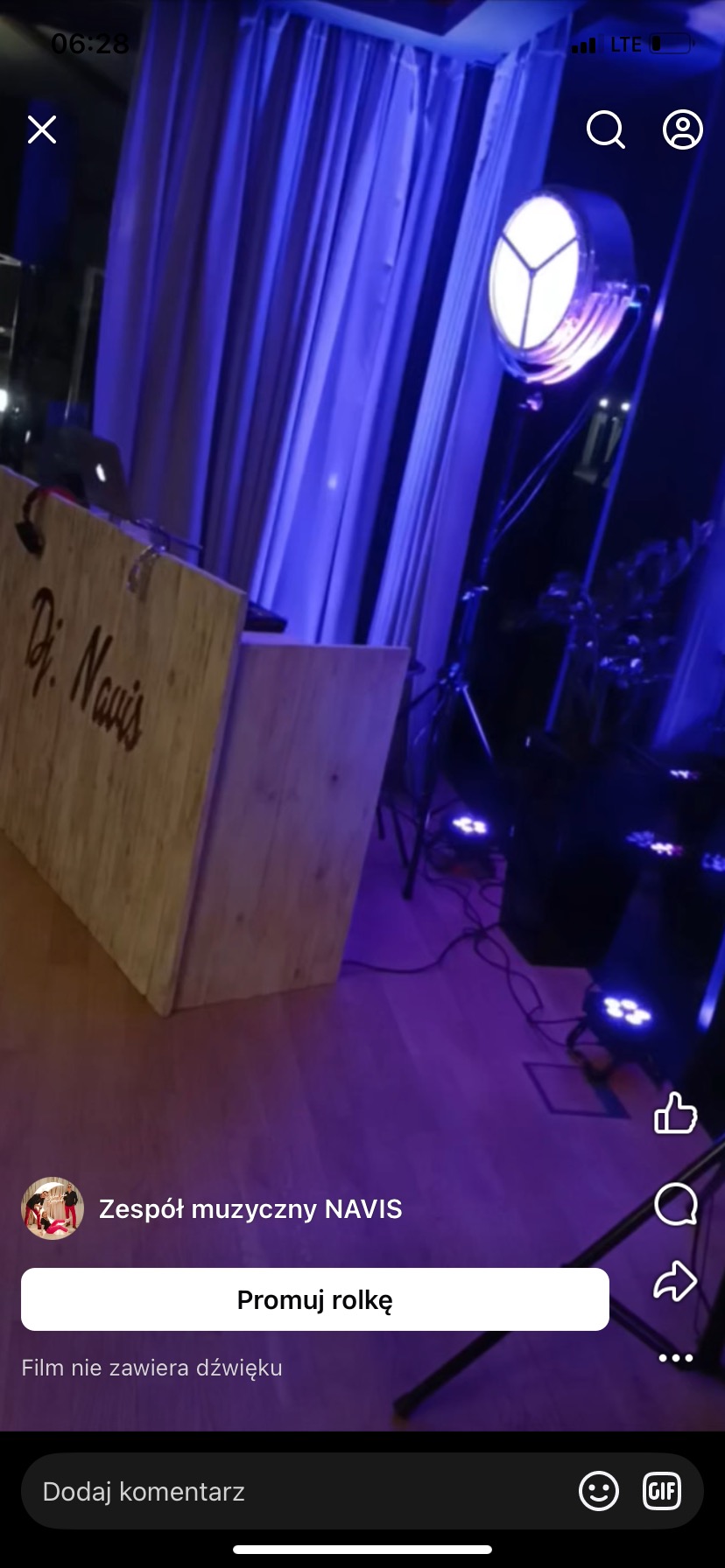 Scena z drewnianym stanowiskiem DJ'a z napisem 'Dj. Navis', oświetlona fioletowym światłem reflektorów. W tle zasłony i elementy sprzętu muzycznego.