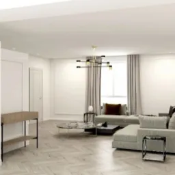 Jasne, przestronne wnętrze salonu z narożną sofą modułową, marmurowym stolikiem kawowym na złotych nóżkach i nowoczesną lampą wiszącą z elementami złota.