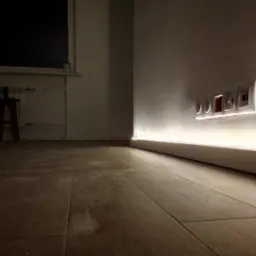 Oświetlenie LED listwy przypodłogowej podkreślające gniazdka elektryczne i włącznik światła na ścianie w nowocześnie urządzonym wnętrzu.