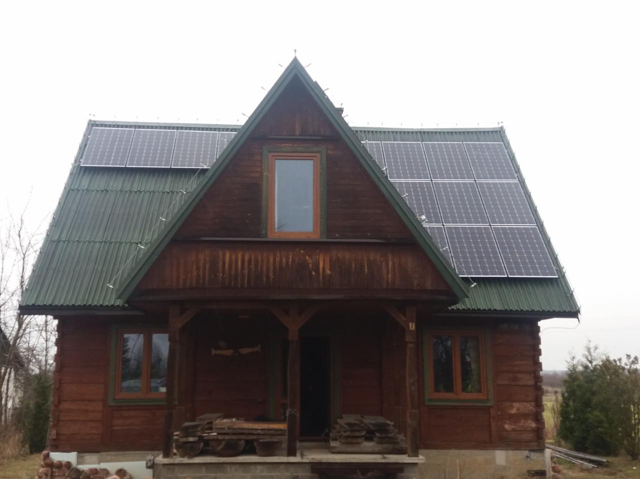 Drewniany dom z panelami słonecznymi na dachu, zielony dach z blachy falistej, Puławy.