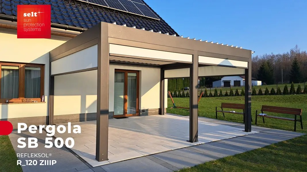 Nowoczesna aluminiowa pergola z zadaszeniem marki Selt, model SB 500, zamontowana przy domu w Szczecinie, z widocznymi panelami słonecznymi na dachu i ławkami w tle.