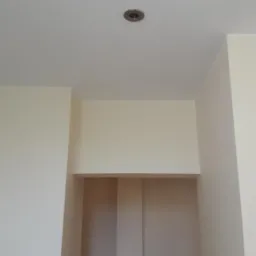 Fragment wnętrza po malowaniu, kremowe ściany i sufit z zamontowanym punktowym oświetleniem halogenowym.