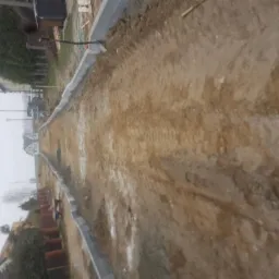 Przygotowanie podłoża pod budowę drogi, widoczne ułożone obrzeża chodnikowe i ubita ziemia.