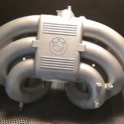 Kolektor dolotowy BMW po renowacji, pokryty srebrną powłoką, widoczne logo producenta.