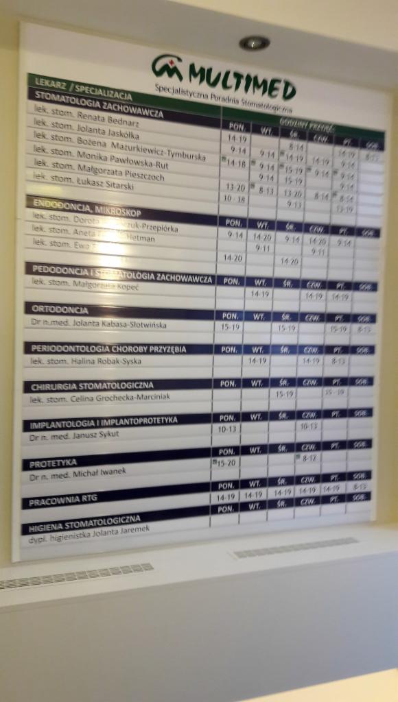 Tablica informacyjna z listą lekarzy specjalistów i godzinami przyjęć w poradni stomatologicznej Multimed, z podziałem na specjalizacje: stomatologia zachowawcza, endodoncja, ortodoncja...