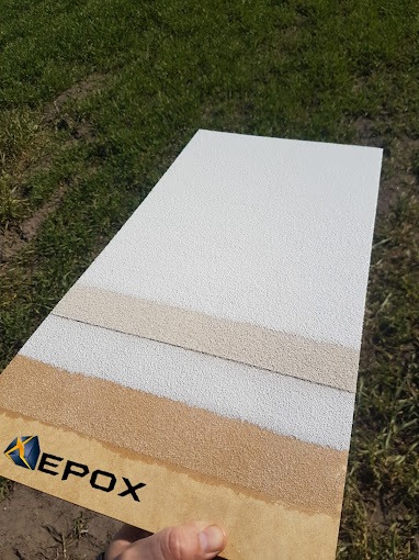 Paleta próbek z różnymi warstwami i teksturami, prawdopodobnie posadzki, z logo firmy 'EPOX' w lewym dolnym rogu, na tle trawy.