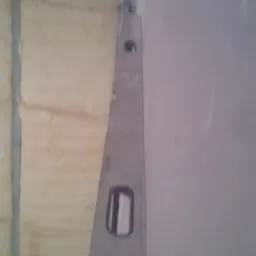 Ściana z nałożoną pianą izolacyjną, sprawdzana poziomicą, przygotowana do dalszych prac wykończeniowych.